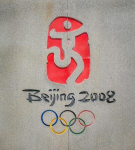 Close-up of the Beijing 2008 Olympic logo and rings on a concrete wall.