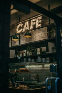 Warm and inviting cafe interior showcasing a decorative illuminated sign and shelves filled with items.